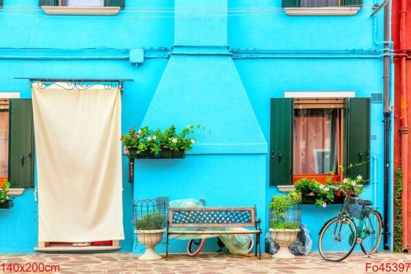 blue aqua colored house with flowers, bench and a bicycle. colorful houses in burano island near venice, italy.