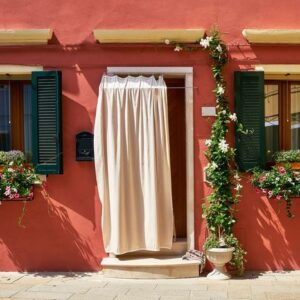 front of the red house with flowers on the island of burano. venice, italy