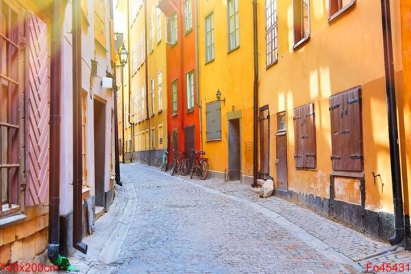 the narrow cobblestone street with a bicycles and yellow red medieval houses of gamla stan historic old center of stockholm at summer sunny day.