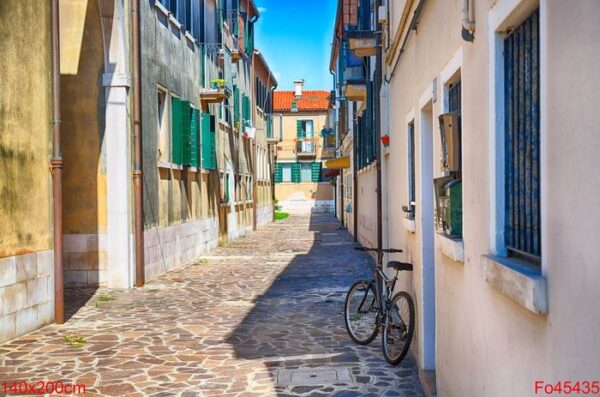 narrow street with a bicycle in the morning in murano island, venice, italy