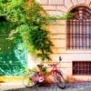 old house wall in trastevere, rome, italy with a red bicycle and green door. old cozy street in rome