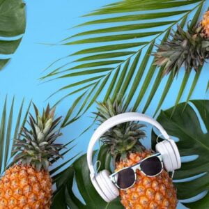 funny pineapple wearing white headphone isolated on blue background.