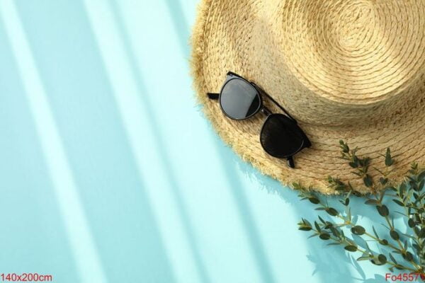 straw hat, branch and sunglasses on blue background