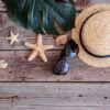 beach accessories: glasses and hat with shells and sea stars on a colored background