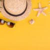 beach accessories: glasses and hat with shells and sea stars on a colored background