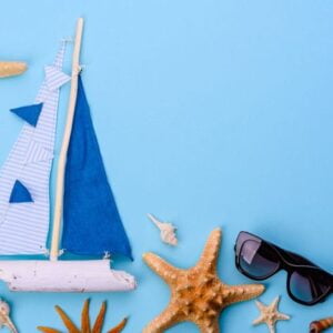 beach accessories: glasses and hat with shells and sea stars on a colored background