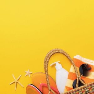 beach bag with leisure accessories on yellow background and copy