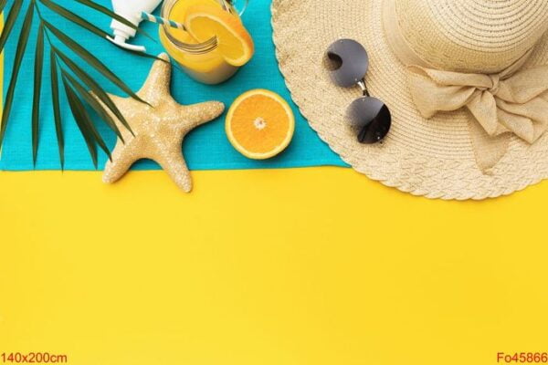 beach holiday accessories, orange juice and palm leaf on a yello