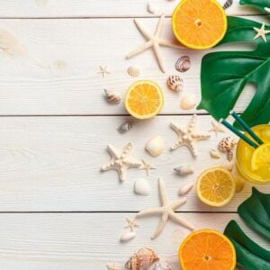 citrus cooling drink on the background of shells and tropical leaves.