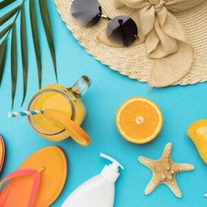 flat composition with beach holiday accessories and fruits on bl