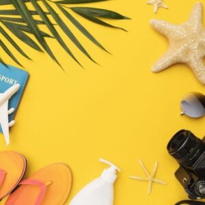 flat composition with beach holiday accessories on yellow backgr