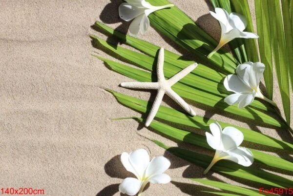 starfish with plumeria flowers on tropical palm leaves on sand.