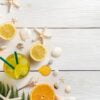 summer background with fruit and a cooling drink. oranges, lemons, juice and shells on a white background.