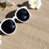 sunglasses with white plumeria flower on sand. summer backgroun