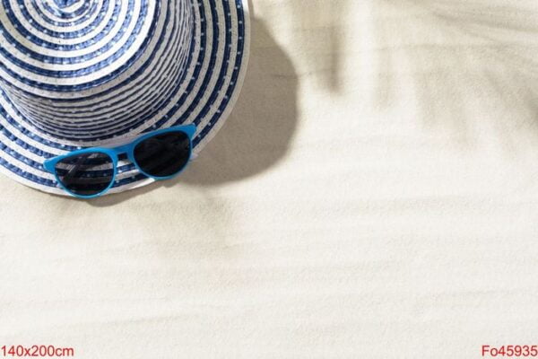 top view of hat on sand with and blue sunglasses