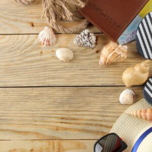 travel concept hat, glasses, flip flops and shells on a natural wooden table. relaxation. holidays. top view. free space