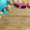 travel concept hat, glasses and shells on a natural wooden table. relaxation. holidays. top view. free space