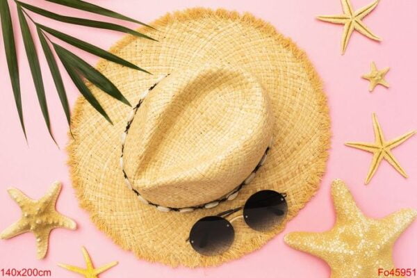 womens straw hat, sunglasses, starfish and palm leaf on a pink b