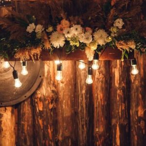 the wooden wall is decorated with electric lamps and flowers. wedding decorations rustic