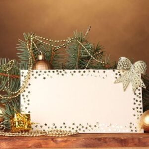 blank postcard, christmas balls and fir tree on wooden table on brown background