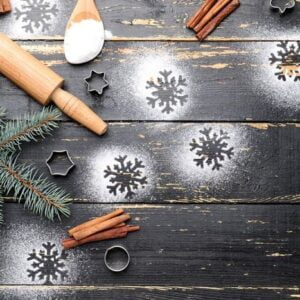 christmas composition with cookie cutters and flour on dark wooden background