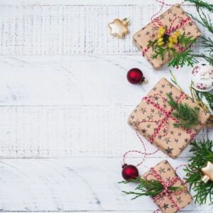 christmas background with fir branches, toys, gift box and bells on wooden old background table. selective focus. top view with copy space