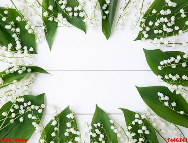 frame made of leaves of lily of the valley on a white wooden background.