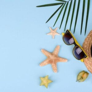 fruit carambol, beach accessories and foliage of a tropical plant on colored paper