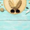 hat, sunglasses and various seashells on a blue wooden backgroun