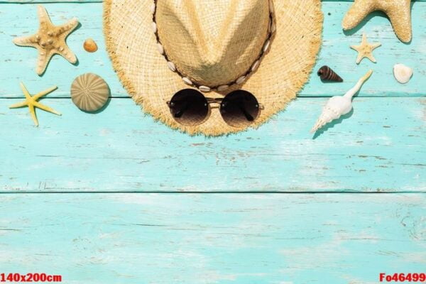 hat, sunglasses and various seashells on a blue wooden backgroun