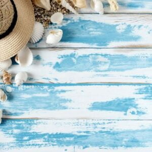 seashells on blue wooden board with straw hat and sunglasses.