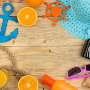 summer accessories. beach accessories. hat, sunscreen, sunglasses, camera, and orange on a natural wooden table. top view. space for text