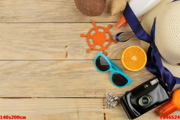 summer accessories. beach accessories. hat, sunscreen, sunglasses, camera, and orange on a natural wooden table. top view. space for text