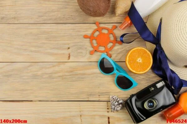 summer accessories. beach accessories. hat, sunscreen, sunglasses, camera, and orange on a natural wooden table. top view. space for text