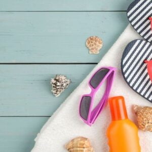 summer accessories. beach accessories. slaps, towel, and sunglasses on a blue wooden table. top view. place for text.