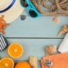 summer accessories. beach accessories. slippers, hat, shells, towel, and sunglasses on a blue wooden table. top view.