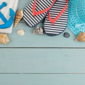 summer accessories. beach accessories. spanking, hat, shells and towel on a blue wooden table. top view. space for text