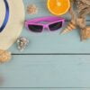 summer accessories. beach accessories. sunscreens, a hat, shells, and sunglasses on a blue wooden table. top view. place for text.