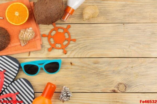 summer accessories. beach accessories. sunscreens, sunglasses, flip flops, and an orange on a natural wooden table. top view. free place