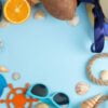 summer accessories with coconut, orange, sun glasses and shells, on a bright blue background. free space. top view. frame