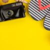 summer accessories with shells, flip flops, a camera on a bright yellow background. top view.