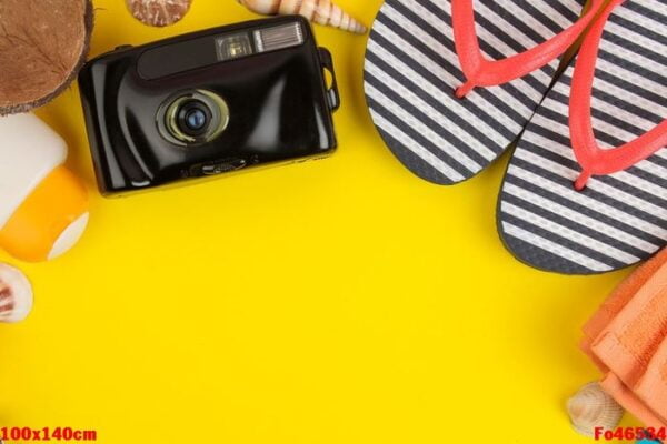 summer accessories with shells, flip flops, a camera on a bright yellow background. top view.