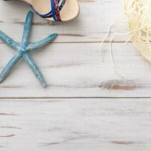 summer background concept: female sandals, starfish, straw hat on light wooden surface