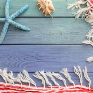 summer background: fringed pareos, seashells on a blue wooden background