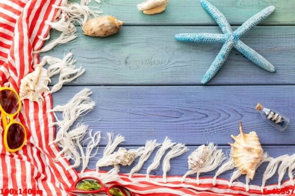 summer background: fringed pareos, seashells, sun goggles, starfish on a blue wooden background