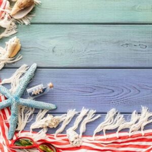 summer background: fringed pareos, seashells, sun goggles, starfish on a blue wooden background