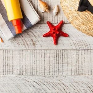 summer background. hat, seashells, sunscreen on a wooden background. copy space.