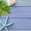 summer background: multicolored starfish, coral, fern, seashell on a blue wooden background