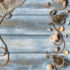 summer interior decoration with starfishes, seashells, ropes and bottles with stones on blue wooden background. copy space. still life. flat lay