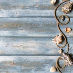 summer interior decoration with starfishes, seashells, ropes and bottles with stones on blue wooden background. copy space. still life. flat lay